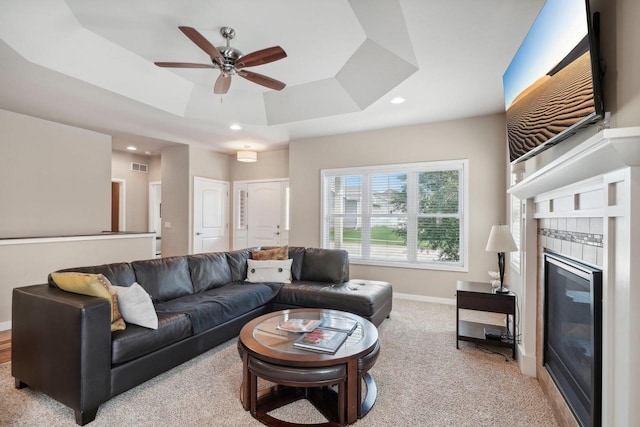 carpeted living area featuring recessed lighting, visible vents, baseboards, a tray ceiling, and a tiled fireplace