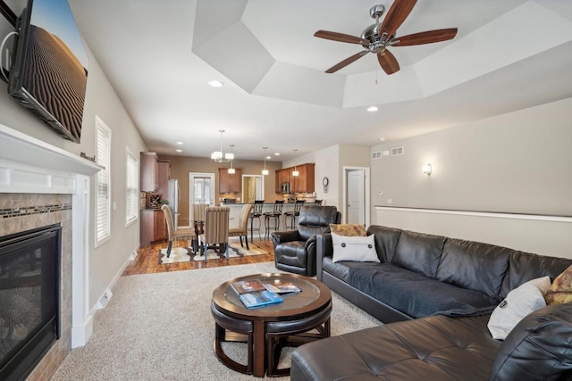 living area featuring a fireplace, recessed lighting, light carpet, baseboards, and ceiling fan with notable chandelier