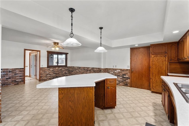 kitchen featuring a center island, brick wall, a wainscoted wall, and light floors