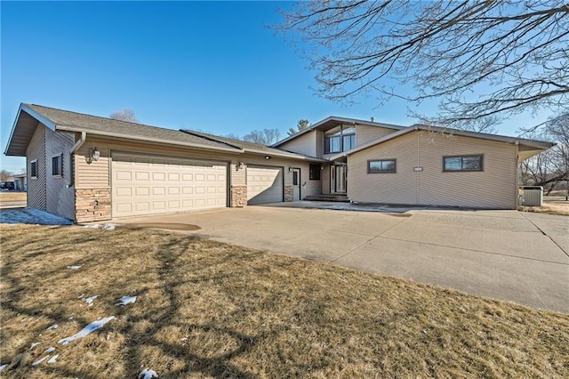 view of front of property featuring a garage, concrete driveway, stone siding, and central air condition unit