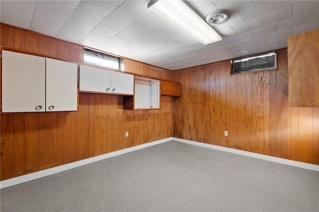 basement with carpet, wooden walls, and baseboards