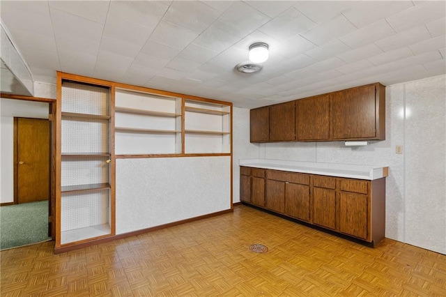 kitchen featuring light countertops, brown cabinetry, and baseboards