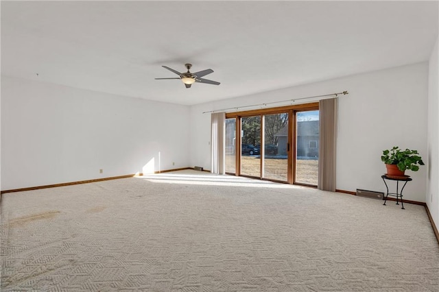 carpeted spare room with ceiling fan and baseboards