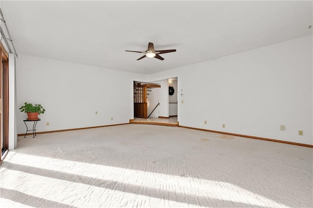 unfurnished room with ceiling fan, baseboards, and light colored carpet