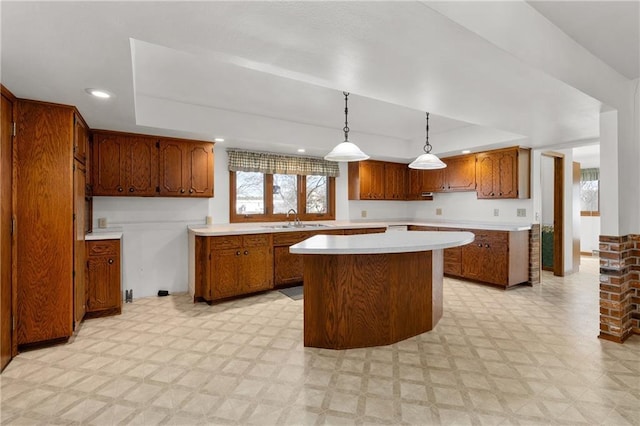 kitchen featuring light floors, a tray ceiling, light countertops, and a sink