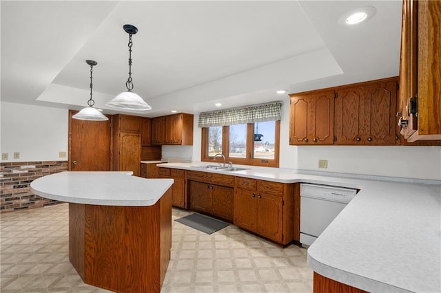 kitchen with dishwasher, a tray ceiling, light countertops, light floors, and a sink