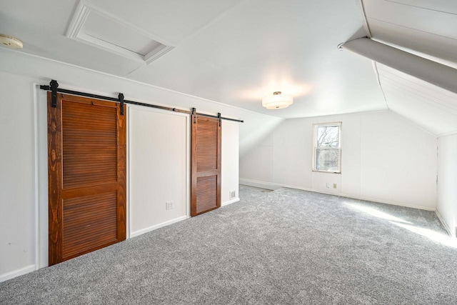 additional living space featuring attic access, a barn door, baseboards, lofted ceiling, and carpet flooring