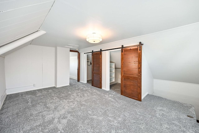 bonus room with carpet floors, vaulted ceiling, and a barn door