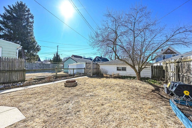 view of yard featuring a fenced backyard, a fire pit, and an outbuilding