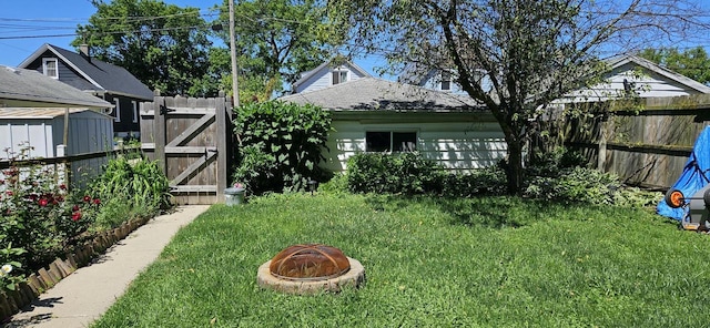 view of yard featuring an outdoor fire pit, fence, and a gate