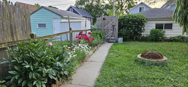 view of yard with a gate, a fire pit, and fence