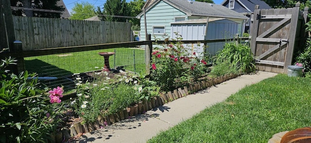 view of yard featuring a gate, fence, and an outdoor structure