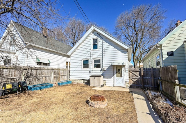 rear view of property featuring a fire pit and fence