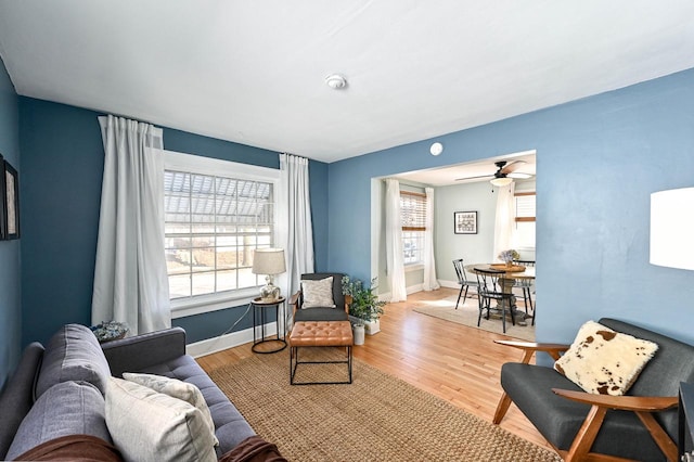 living area with ceiling fan, light wood finished floors, and baseboards