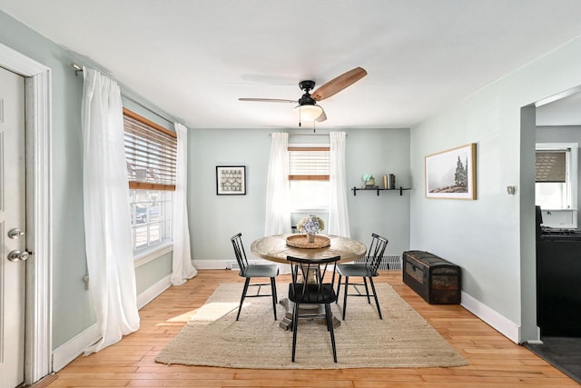 dining space featuring ceiling fan, light wood finished floors, and baseboards