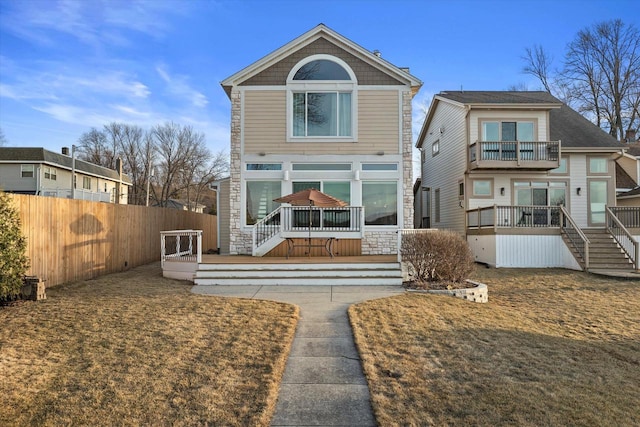 rear view of house with a balcony, fence, and a wooden deck