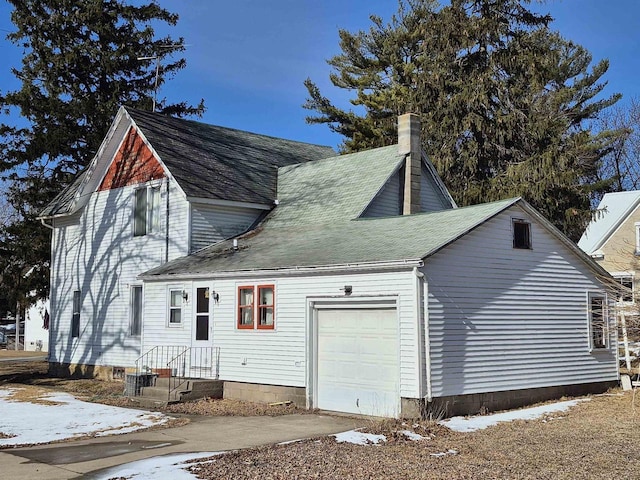 view of front facade with a garage, driveway, and a chimney