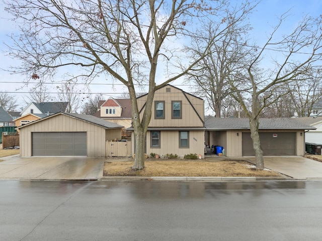 view of front of home featuring a shingled roof, a detached garage, and fence