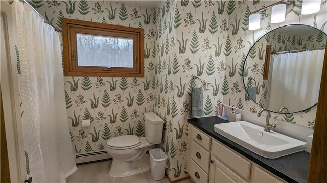 14091 W County Highway B, Hayward, WI 54843 - bathroom featuring a baseboard heating unit, vanity, toilet, and wallpapered walls