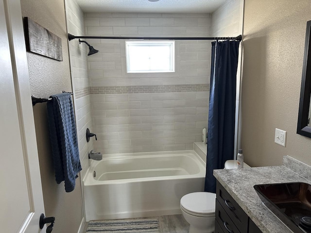 bathroom featuring a textured wall, toilet, wood finished floors, shower / bath combination with curtain, and vanity