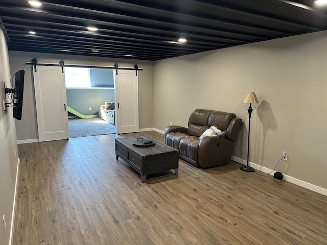 living room featuring light wood-style floors, baseboards, and a barn door