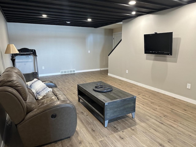 living room featuring light wood-style flooring, visible vents, and baseboards