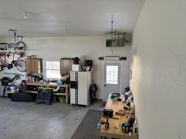 garage with white refrigerator with ice dispenser and a workshop area