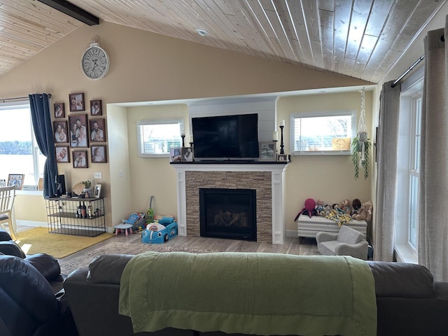 living area featuring baseboards, wooden ceiling, wood finished floors, vaulted ceiling with beams, and a stone fireplace