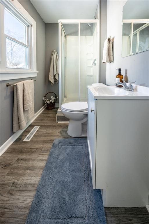 bathroom featuring vanity, a shower stall, wood finished floors, and visible vents