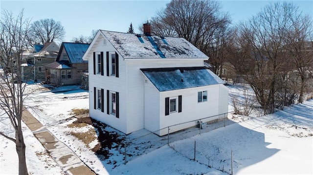 view of snow covered exterior featuring fence, roof with shingles, and a chimney