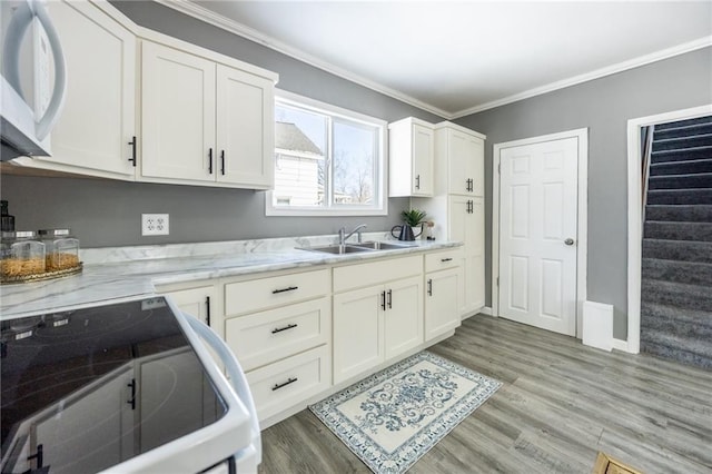 kitchen with crown molding, light wood-type flooring, white appliances, white cabinetry, and a sink