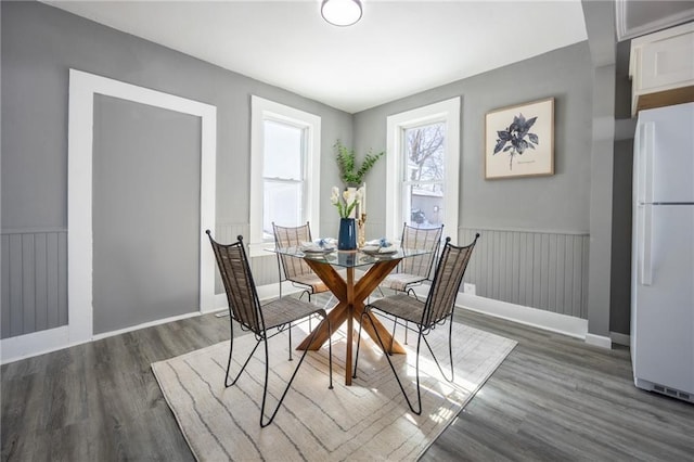 unfurnished dining area featuring a wainscoted wall and wood finished floors