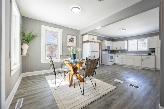 dining room featuring visible vents, a wainscoted wall, light wood finished floors, and baseboards