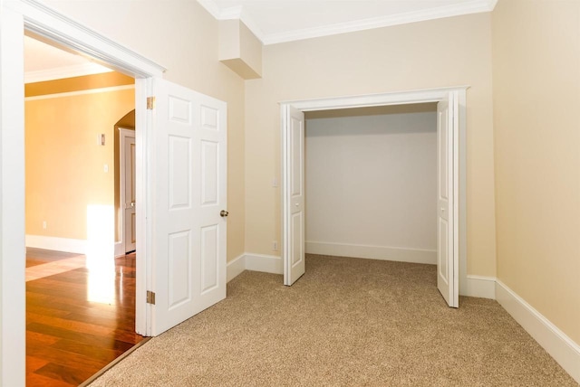 unfurnished bedroom featuring light carpet, baseboards, and crown molding