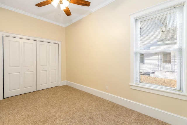 unfurnished bedroom featuring ceiling fan, light carpet, baseboards, ornamental molding, and a closet