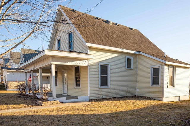 exterior space with covered porch, a shingled roof, and a lawn