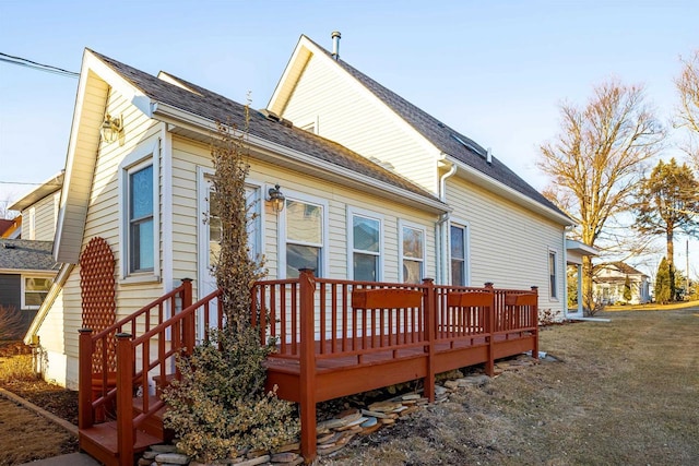 back of property featuring a shingled roof and a deck