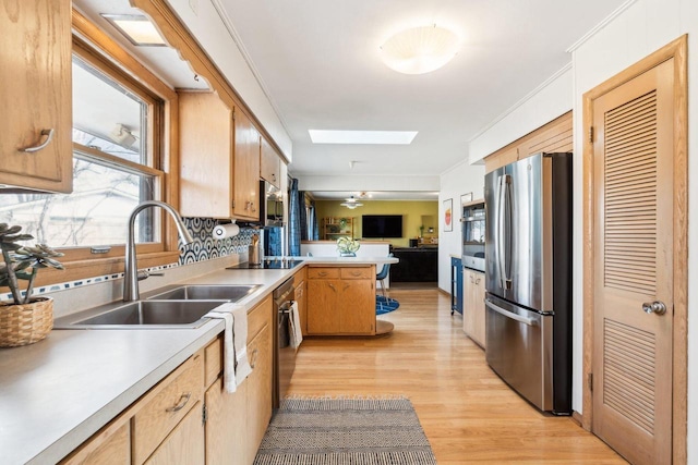 kitchen featuring open floor plan, ornamental molding, appliances with stainless steel finishes, a skylight, and a peninsula