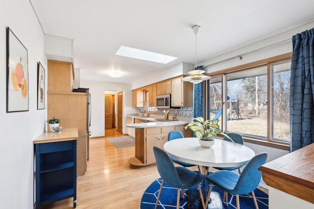 dining area with a skylight and light wood-style floors