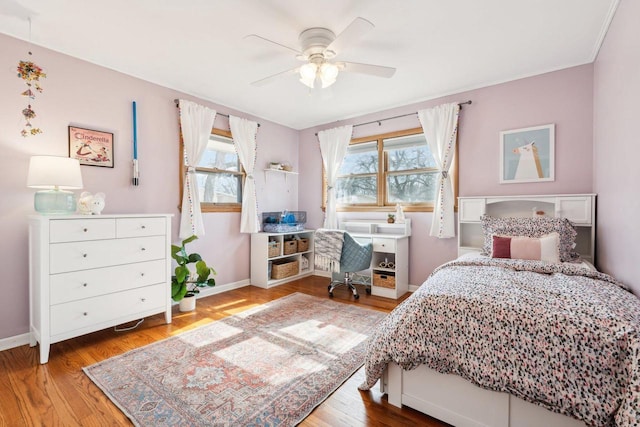 bedroom with a ceiling fan, multiple windows, wood finished floors, and baseboards