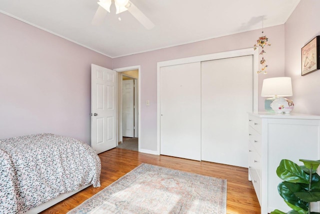 bedroom with light wood-type flooring, a closet, crown molding, baseboards, and ceiling fan