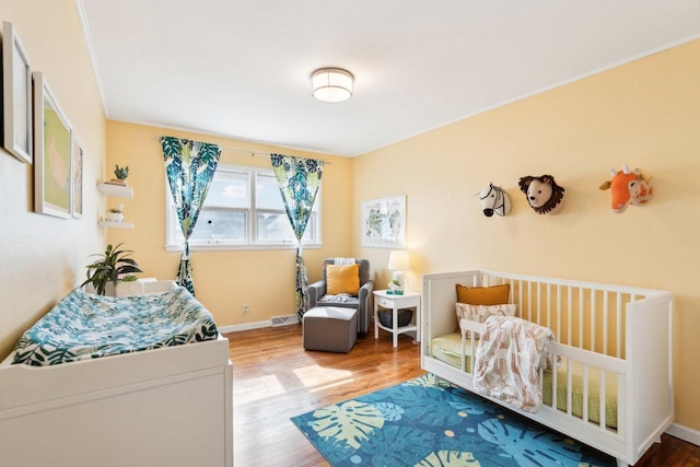 bedroom with visible vents, baseboards, and wood finished floors