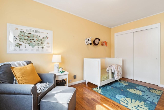 bedroom featuring a closet, crown molding, baseboards, and wood finished floors