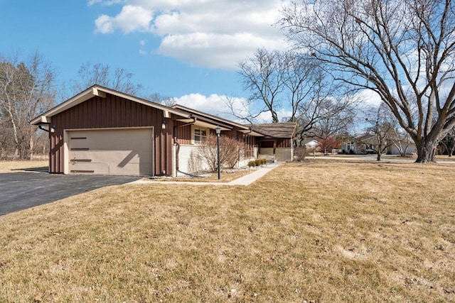 view of front of house featuring aphalt driveway, a front yard, a garage, and brick siding