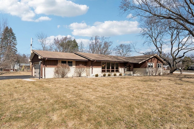 ranch-style home with a front yard, an attached garage, brick siding, and board and batten siding