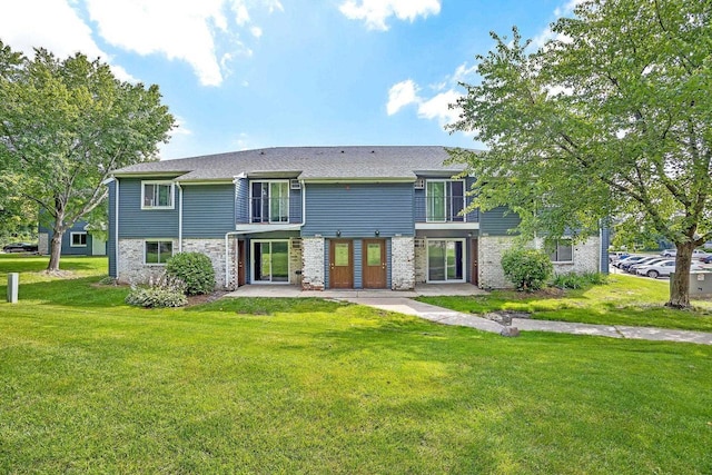 back of property with a balcony, a lawn, and brick siding