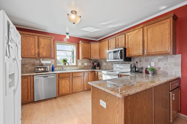 kitchen with a peninsula, light wood-style flooring, brown cabinetry, and appliances with stainless steel finishes