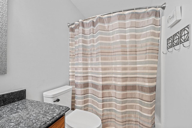 full bath featuring a shower with shower curtain, toilet, and vanity