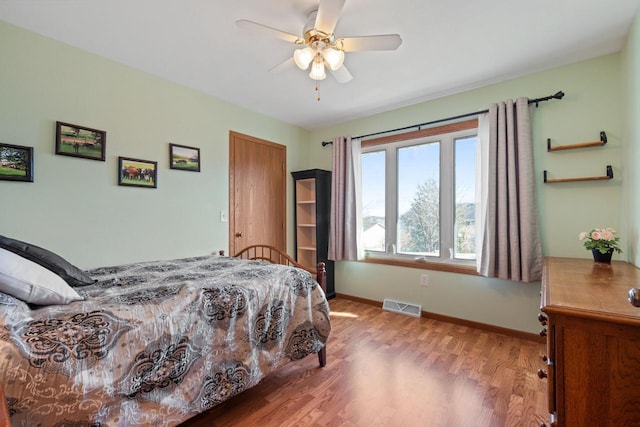 bedroom with visible vents, baseboards, wood finished floors, and a ceiling fan