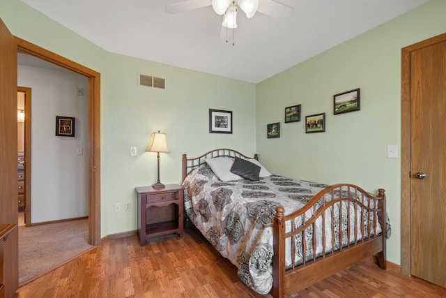 bedroom with ceiling fan, visible vents, baseboards, and wood finished floors